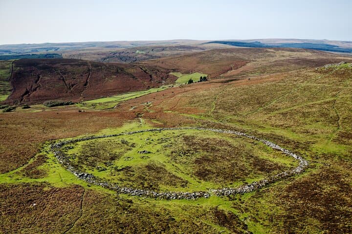 The ancient remains of a Bronze Age settlement, peacefully nestled among rolling moorland hills at Grimspound